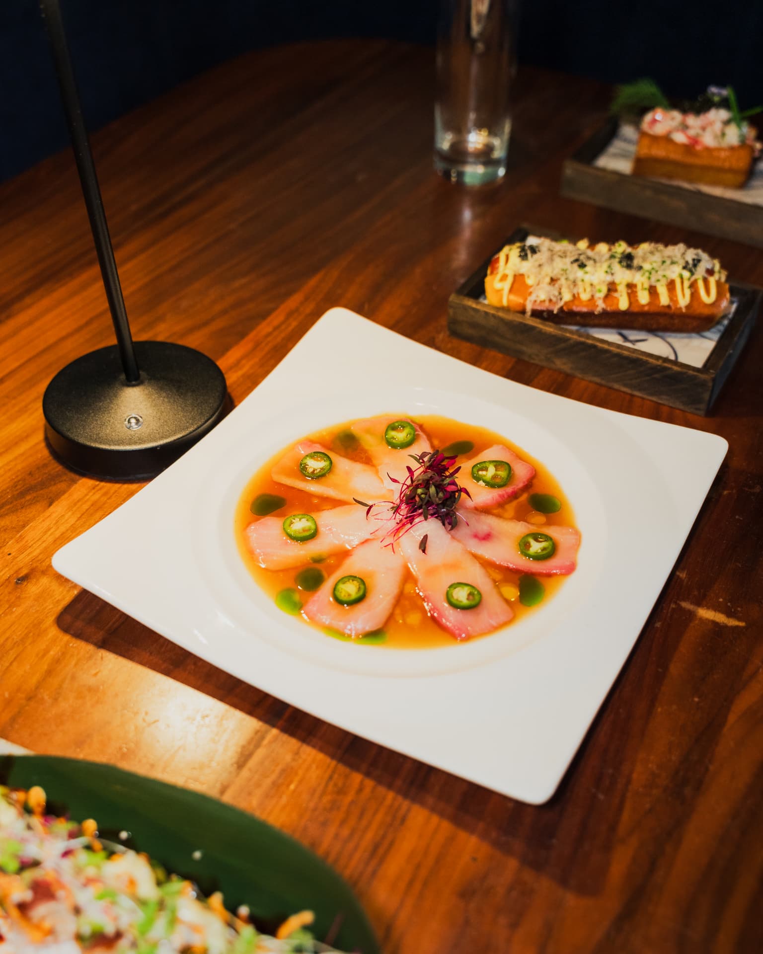Thinly sliced raw fish plated with jalapeño and microgreens at a restaurant