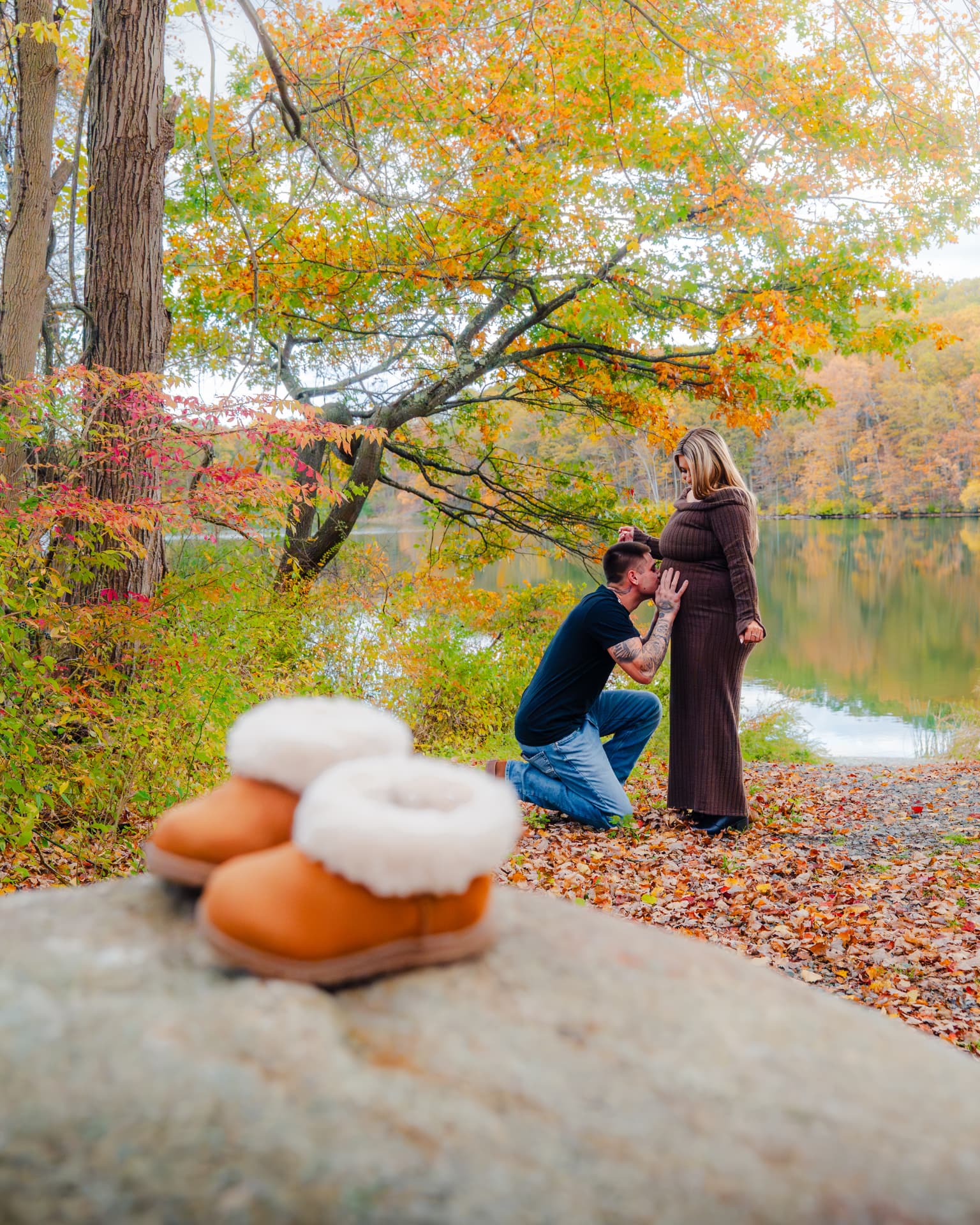 Autumn lakeside pregnancy announcement engagement session with baby booties in the foreground