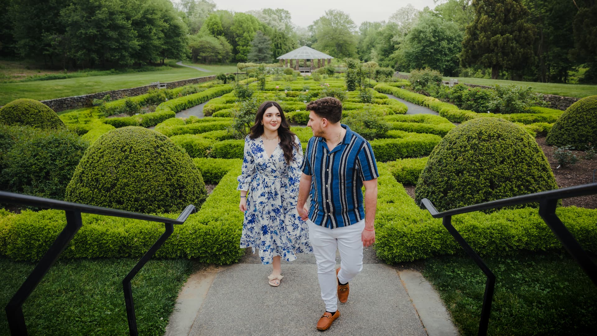 Engaged couple walking through a manicured garden maze